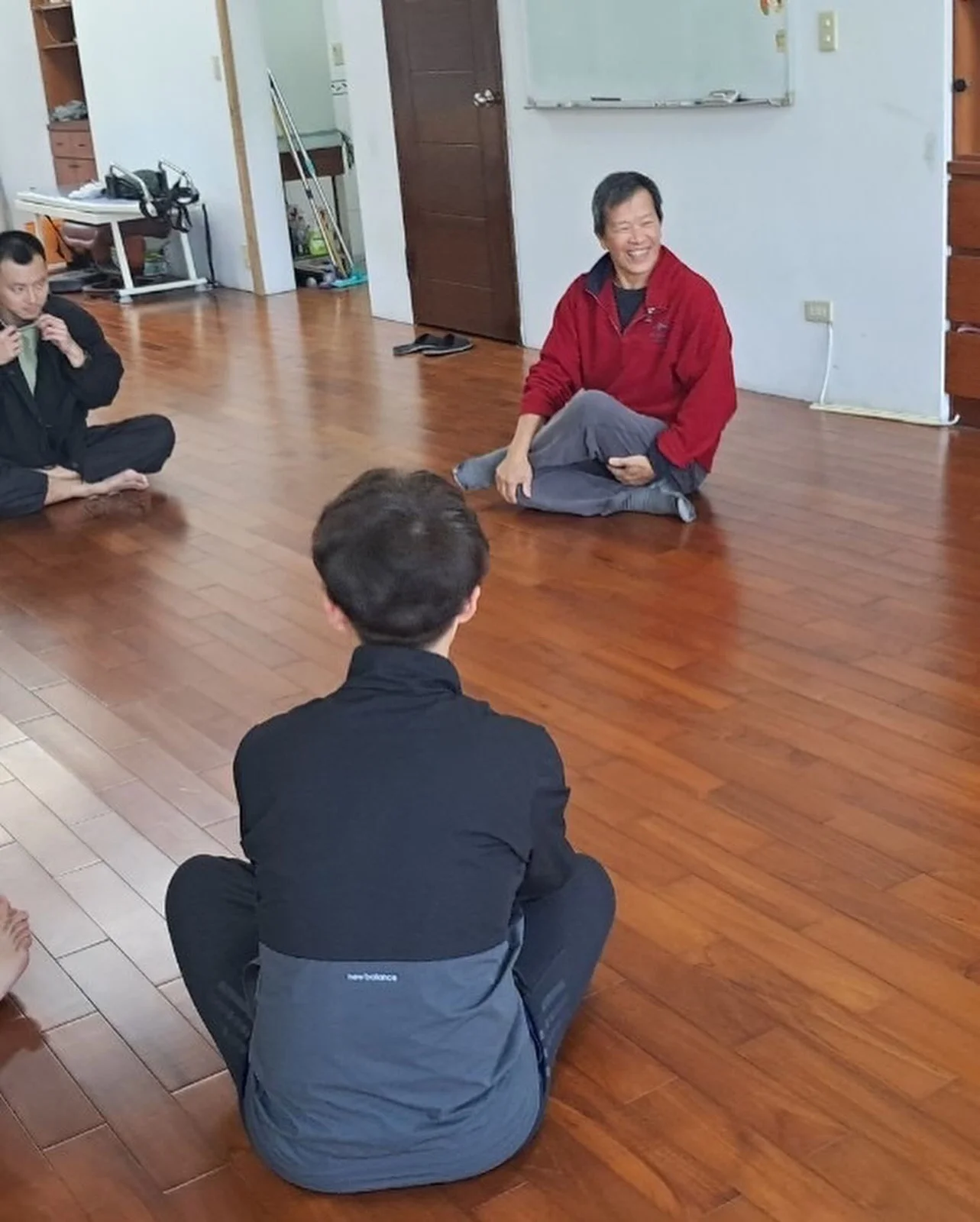 大家盤腿坐在木地板上圍成一圈分享,老師笑著